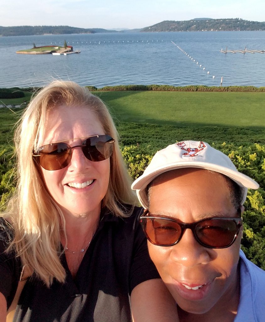 Two woman on a golf course and a lake in the background.