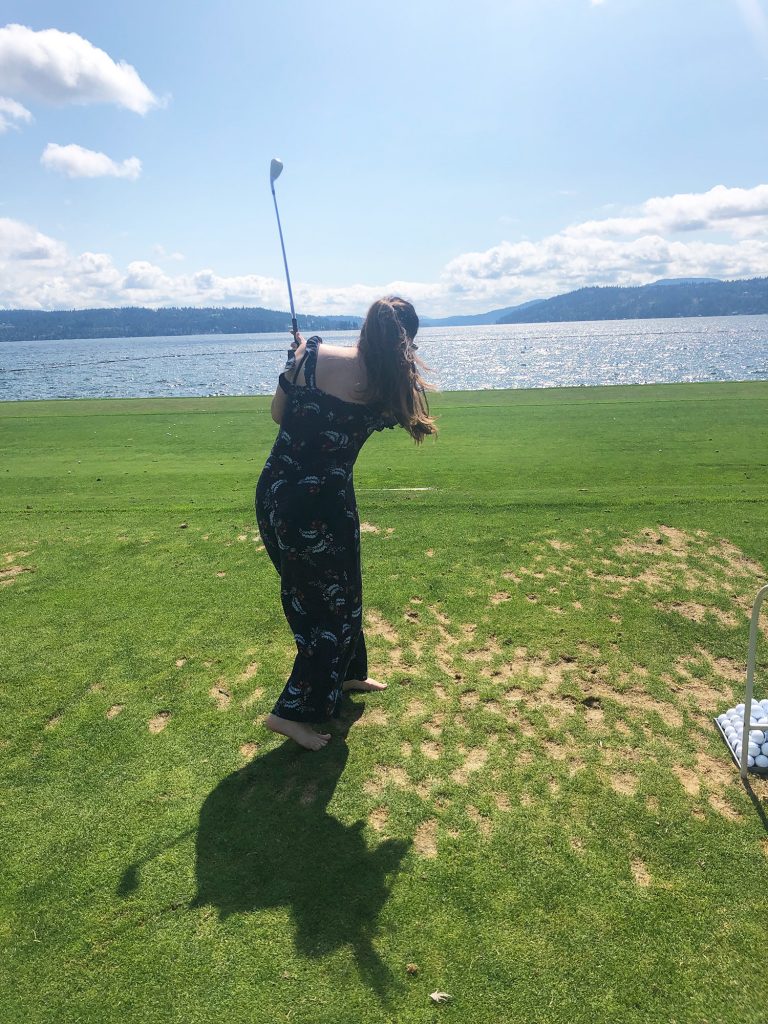 Woman swinging a golf club.